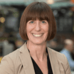 Jayne Haines在米色夹克中,笑得很开心