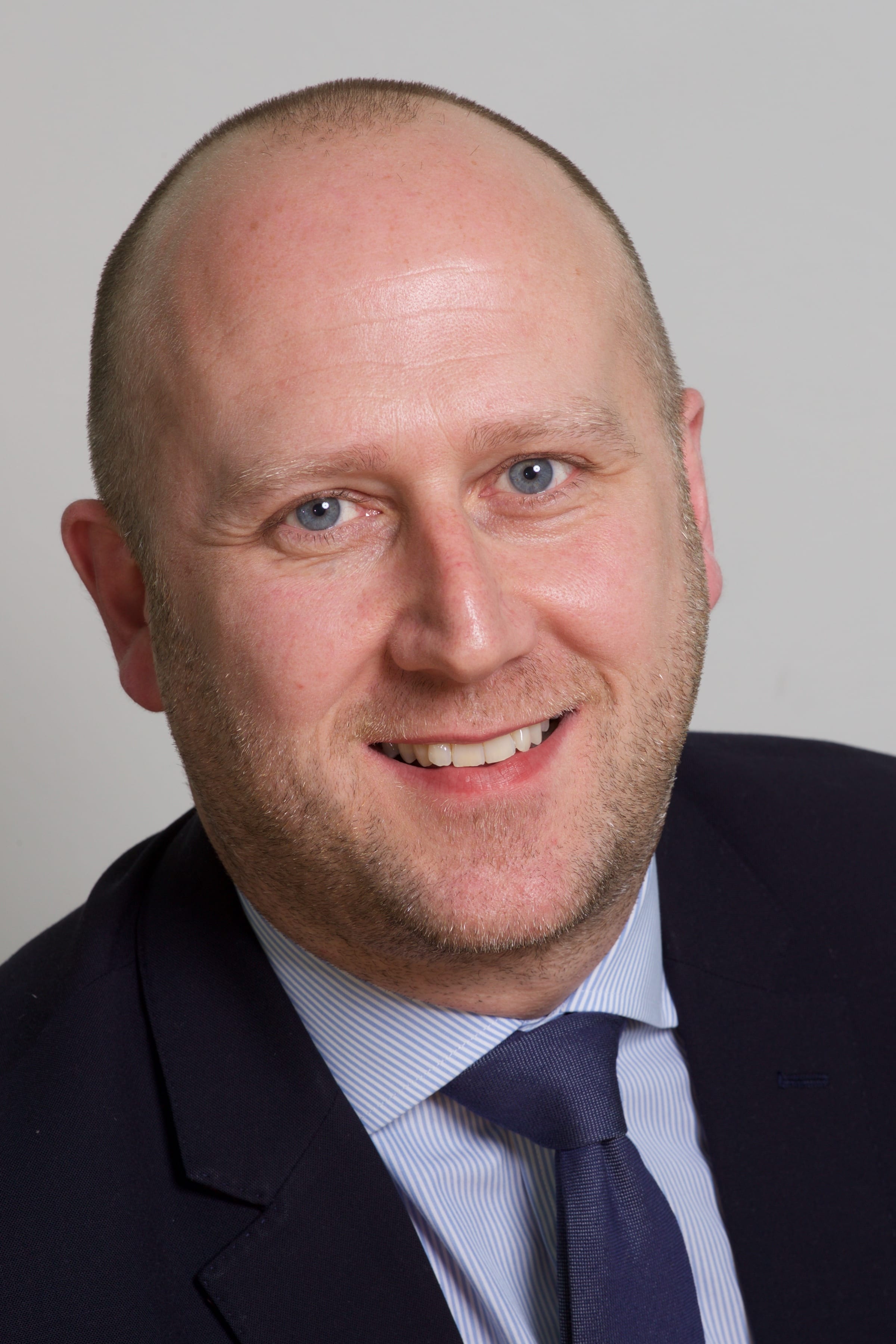 A close up of Mark Allan in a suit with shirt and tie