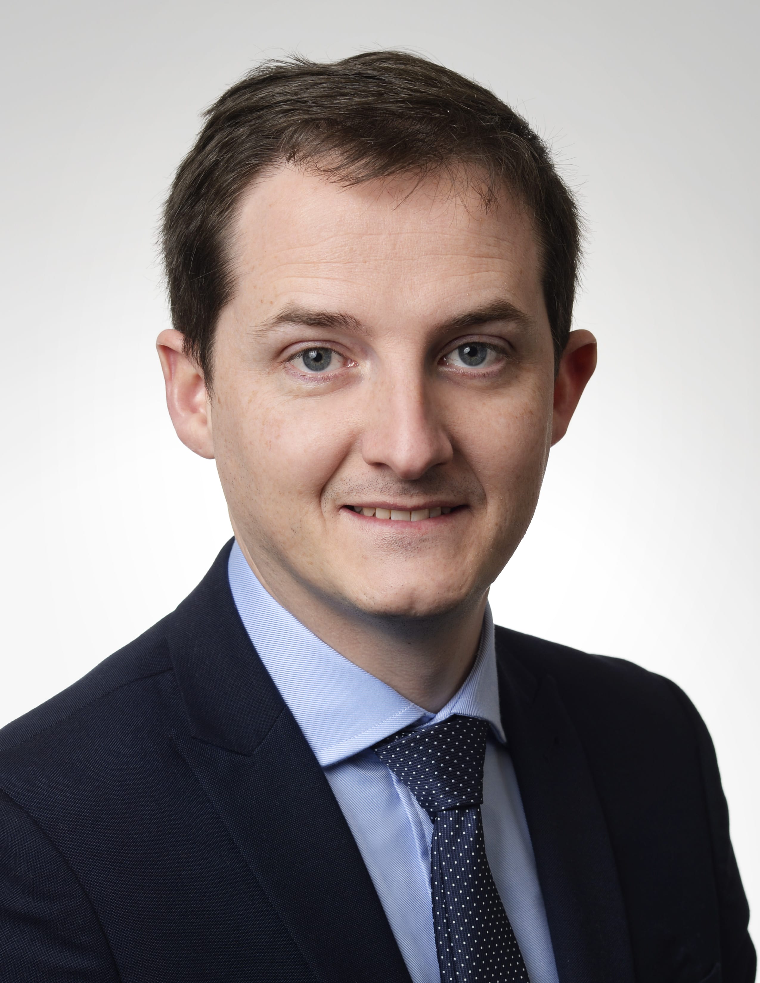Jonathan Evans smiling and wearing a suit